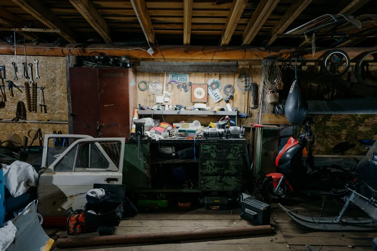 A cluttered garage filled with tools, a motorcycle, and car door parts, highlighting the need for timely repairs.