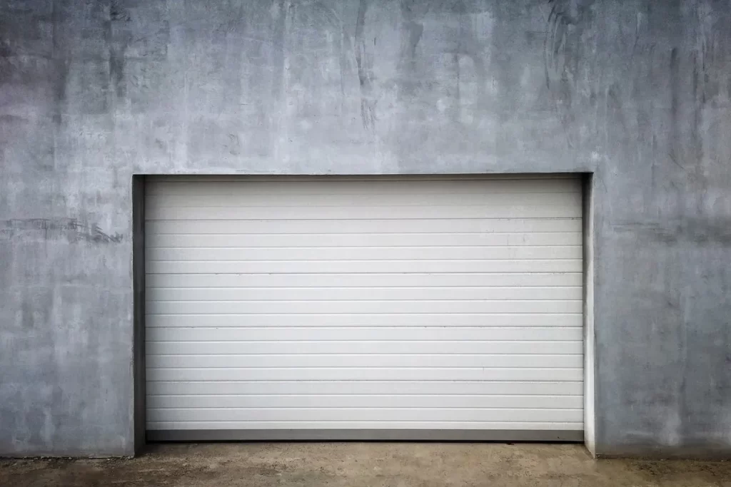 A garage door set against an unfinished concrete wall, highlighting potential repair needs.