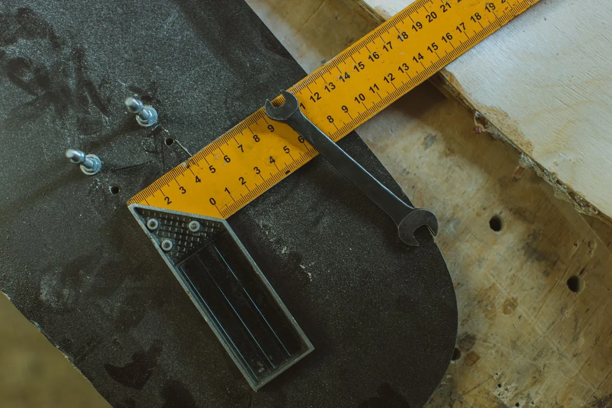 Skateboard assembly tools like a ruler and wrench on a wooden workbench, symbolizing DIY repairs.